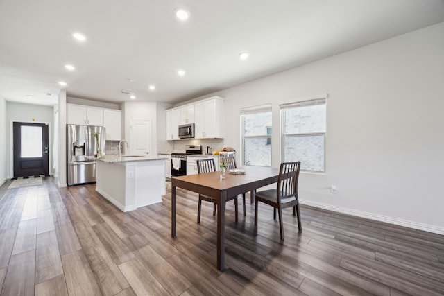 dining room with dark wood-type flooring, recessed lighting, a healthy amount of sunlight, and baseboards