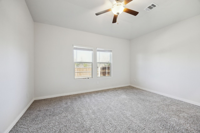 carpeted spare room featuring a ceiling fan, visible vents, and baseboards