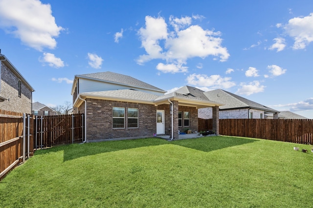 back of property featuring a yard, brick siding, a shingled roof, and a fenced backyard