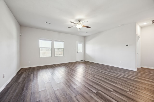 unfurnished room featuring dark wood-style floors, visible vents, baseboards, and a ceiling fan