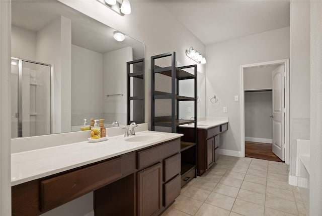 full bath with a spacious closet, a shower stall, vanity, tile patterned flooring, and baseboards