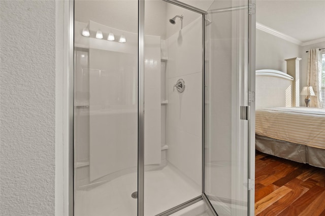 full bathroom with a textured wall, connected bathroom, wood finished floors, a stall shower, and crown molding