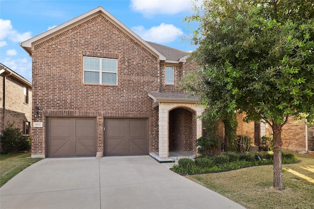 traditional-style house featuring brick siding, roof with shingles, a front yard, a garage, and driveway