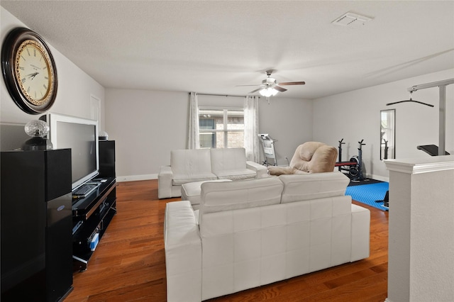 living room with baseboards, ceiling fan, visible vents, and wood finished floors