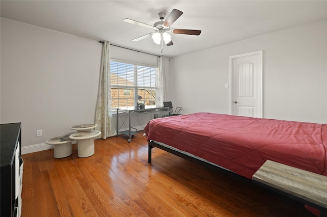 bedroom featuring ceiling fan, baseboards, and wood finished floors