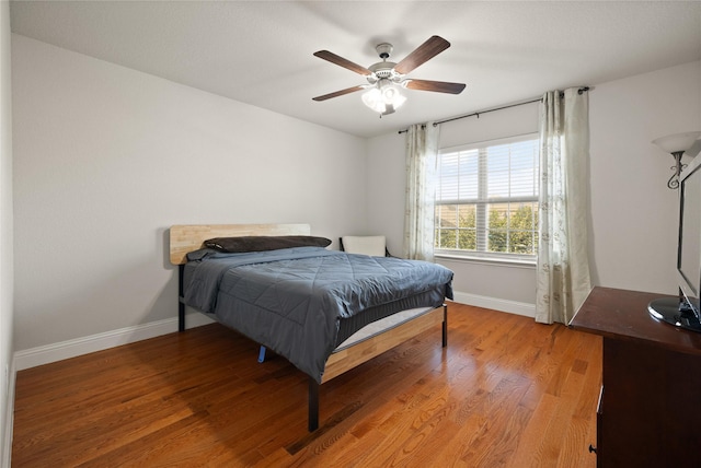 bedroom featuring ceiling fan, baseboards, and wood finished floors