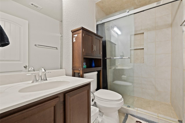 full bathroom with a stall shower, visible vents, a textured wall, toilet, and vanity