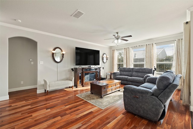 living room featuring arched walkways, visible vents, baseboards, dark wood finished floors, and crown molding