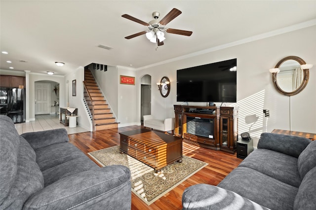 living area with arched walkways, stairway, wood finished floors, and visible vents