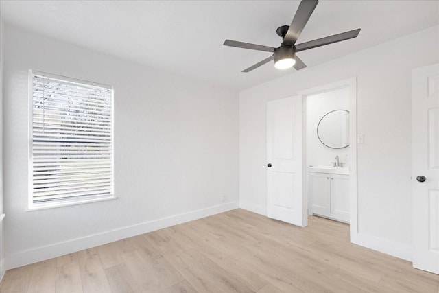 unfurnished bedroom featuring light wood-style floors, a ceiling fan, baseboards, and a sink