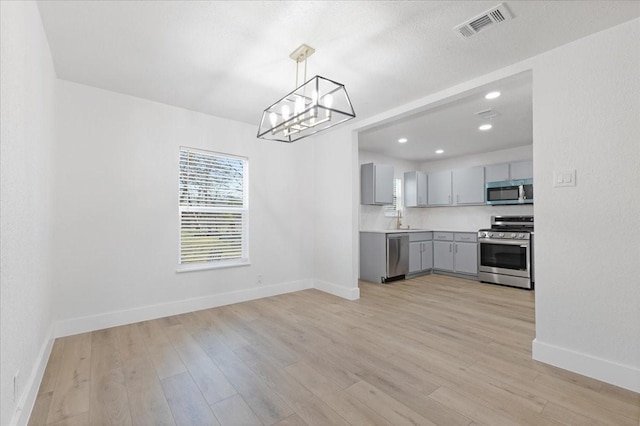 kitchen with stainless steel appliances, light wood-style flooring, visible vents, and gray cabinetry