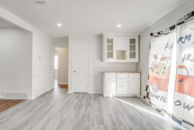 interior space with light wood-type flooring, visible vents, and ornamental molding