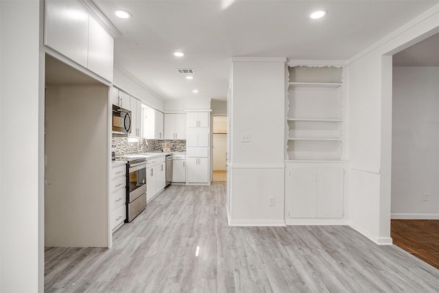 kitchen with stainless steel appliances, white cabinets, light wood finished floors, light countertops, and tasteful backsplash