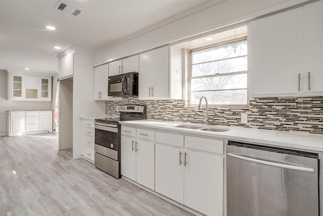 kitchen featuring tasteful backsplash, appliances with stainless steel finishes, light countertops, white cabinetry, and a sink