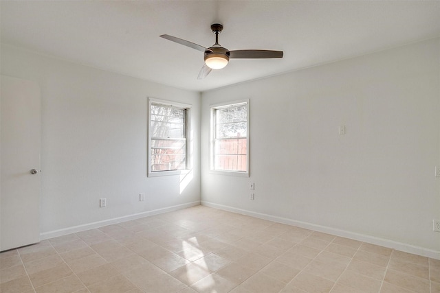 spare room with ceiling fan and baseboards