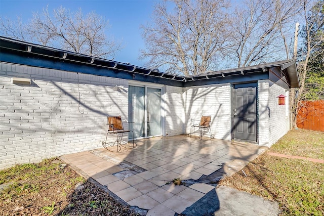 rear view of property featuring a patio, brick siding, and fence