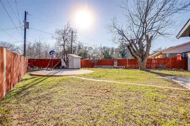 view of yard with a shed, a fenced backyard, and an outbuilding