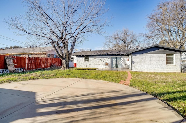 exterior space with brick siding, fence, and a lawn