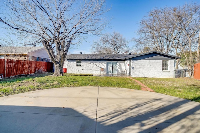 back of house with brick siding, fence, and a lawn