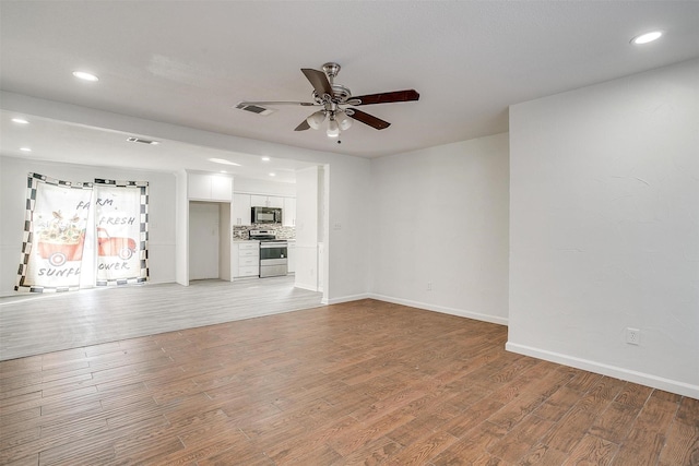 unfurnished living room with ceiling fan, wood finished floors, visible vents, and baseboards