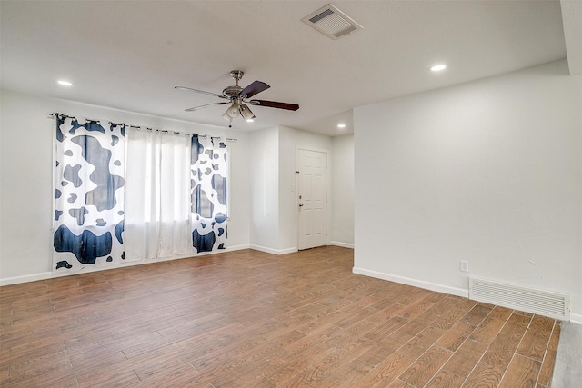 spare room featuring a ceiling fan, visible vents, and wood finished floors