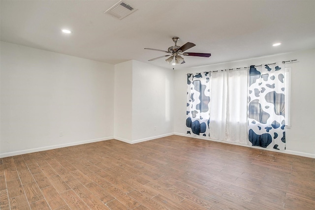 spare room with a ceiling fan, baseboards, visible vents, and wood finished floors