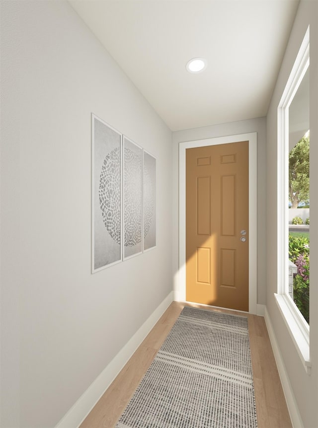 doorway to outside featuring baseboards and wood finished floors