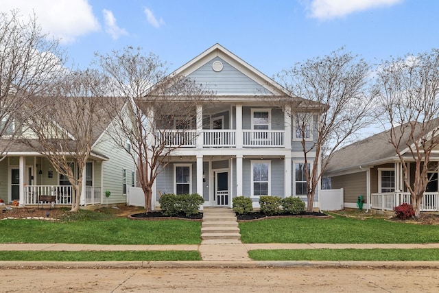 neoclassical home featuring covered porch, a front yard, and a balcony