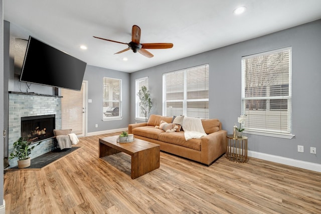 living area featuring light wood-style floors, a fireplace, and baseboards