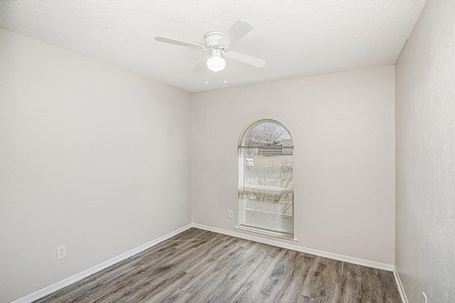 empty room featuring ceiling fan, a textured ceiling, baseboards, and wood finished floors