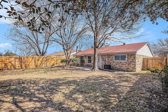 back of house with a fenced backyard, brick siding, and central AC unit