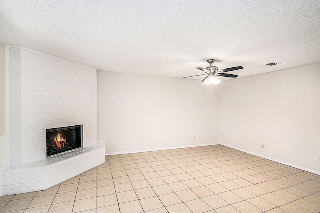 unfurnished living room featuring ceiling fan, a textured ceiling, a fireplace, visible vents, and baseboards