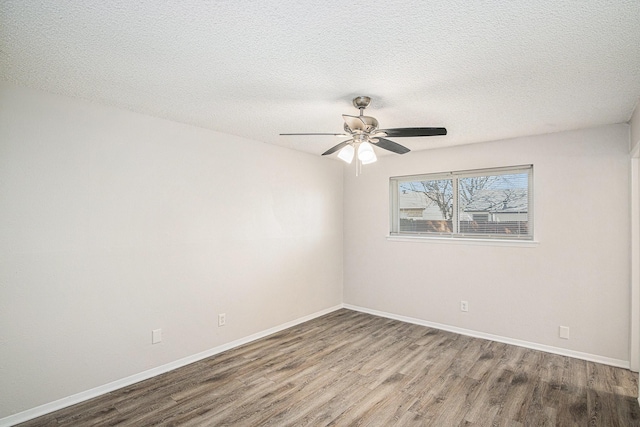 empty room featuring a textured ceiling, ceiling fan, wood finished floors, and baseboards