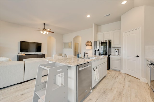 kitchen featuring open floor plan, stainless steel appliances, a kitchen island with sink, and white cabinetry