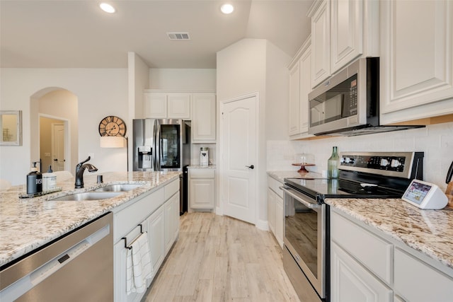 kitchen with light stone counters, visible vents, appliances with stainless steel finishes, white cabinetry, and a sink