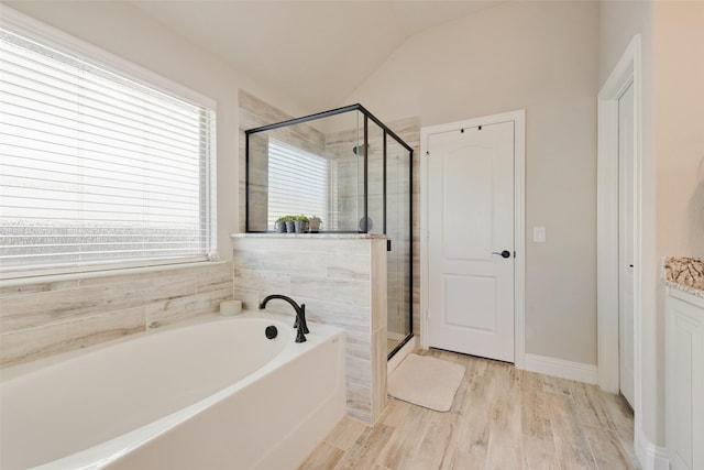 bathroom featuring a garden tub, a shower stall, vaulted ceiling, and wood finished floors