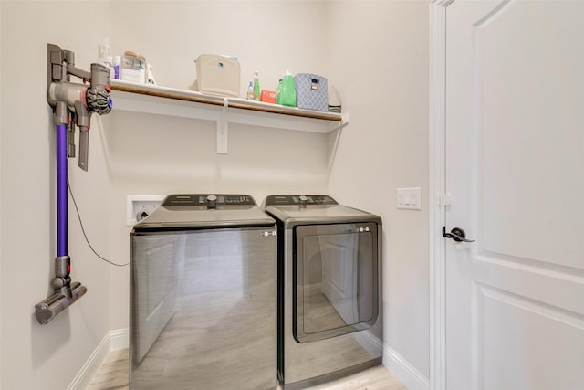 washroom featuring laundry area, washing machine and dryer, baseboards, and light wood-style flooring