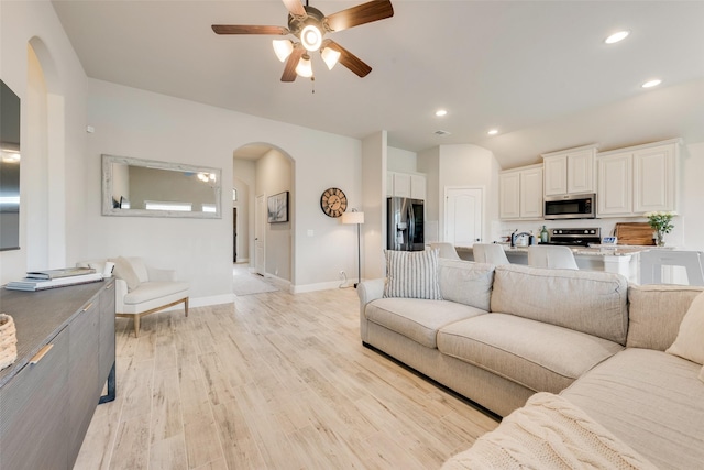 living area with arched walkways, ceiling fan, light wood-style flooring, and recessed lighting