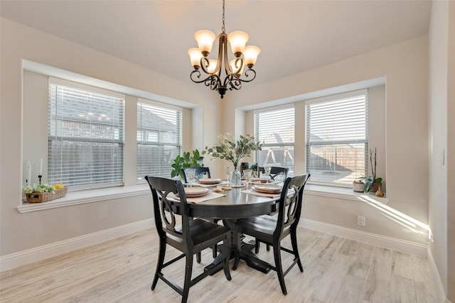 dining area with light wood-style floors, baseboards, and a notable chandelier