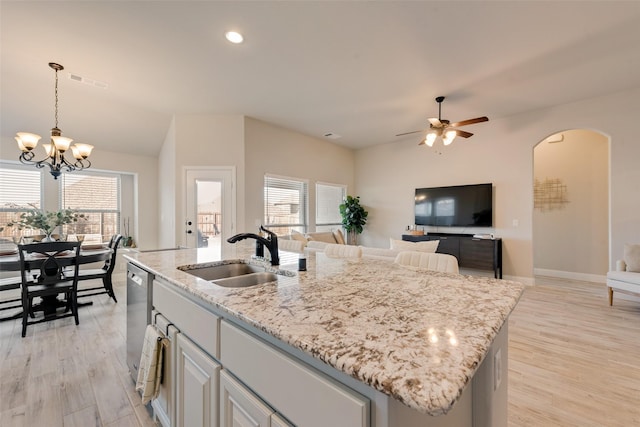 kitchen with a center island with sink, arched walkways, dishwasher, decorative light fixtures, and a sink