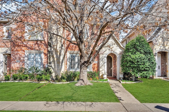 view of front facade with stone siding, brick siding, and a front lawn