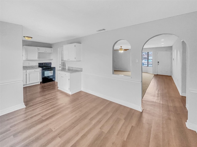 kitchen with visible vents, arched walkways, black electric range oven, light wood-style floors, and white cabinetry