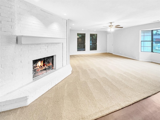 unfurnished living room featuring light carpet, baseboards, ceiling fan, a brick fireplace, and recessed lighting