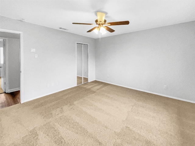 spare room featuring baseboards, visible vents, dark colored carpet, and a ceiling fan