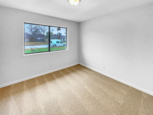 carpeted empty room with a textured ceiling and baseboards