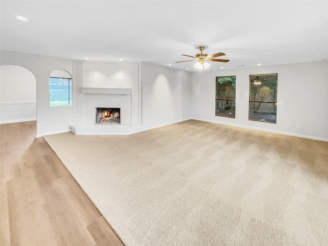 unfurnished living room with a large fireplace, recessed lighting, and baseboards