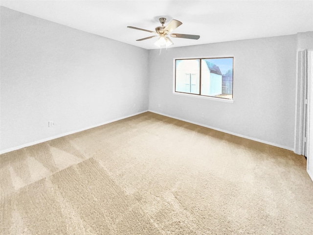 carpeted spare room with baseboards and a ceiling fan