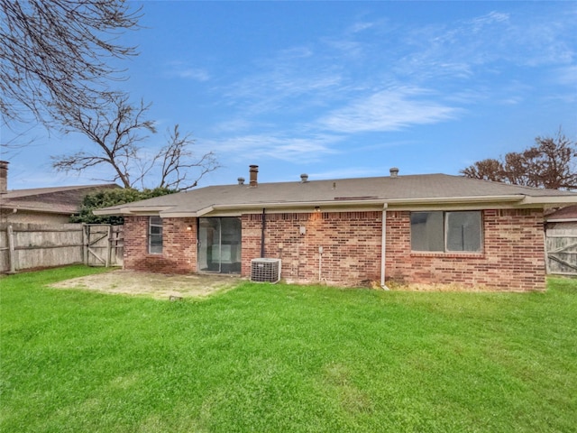 rear view of property with brick siding, fence, and a yard