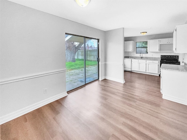 kitchen featuring a sink, wood finished floors, white cabinetry, baseboards, and dishwasher