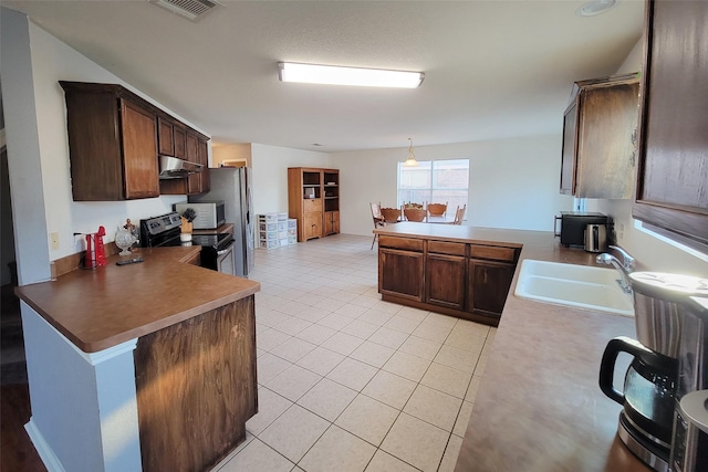 kitchen with light tile patterned floors, stainless steel appliances, a sink, a peninsula, and under cabinet range hood